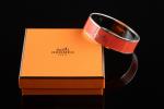 HERMES. 
Bracelet jonc modèle "Calèche" en émail orange vif et...